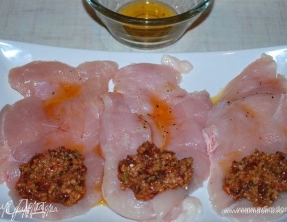 Смазать грудки маслом от вяленых помидоров, посолить и поперчить. На один край куриного филе выложить оливковую начинку, свернуть рулетиком и скрепить деревянной шпажкой.