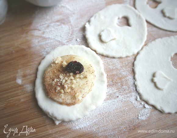 Вырезать из теста кружочки, которые по размеру должны быть немного больше, чем кружочки яблок. В половине кружочков из текста вырезать трафаретом «окошечки». Посыпать кружочки яблок корицей с сахарным песком, орехами, поместить 1–2 штуки сушеной брусники. Можно вставить плоские палочки под диск с яблоком.