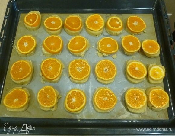 Разогреть духовку до 180°С. Тесто нарезать на кружки 5–7 мм, разложить на противень. Разложить на печенье мандарины. Поставить в духовку на 20–25 минут до золотистого цвета. 