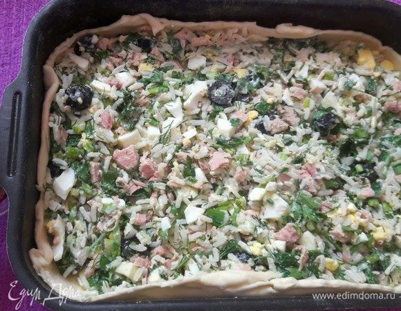 Далее разморозить слоеное тесто (быстрый вариант, можно приготовить с любым). Один пласт раскатать по размеру формы, в которой будете печь пирог, выложить начинку и разровнять. Сверху положить несколько кусочков сливочного масла, так пирог будет более сочным.