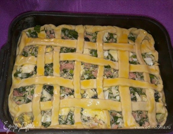 Сделать коврик на будущем пироге, смазать желтком и отправить в разогретую духовку на 20–30 минут.