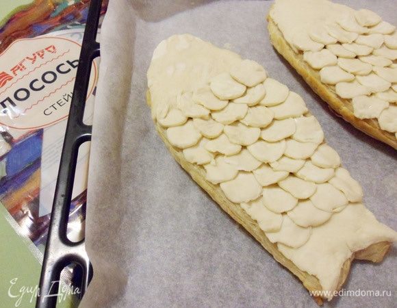 Затем уложить кружочки из теста смазанной стороной вниз, создавая имитацию чешуи. Начинать выкладывать «чешую» с хвоста рыбы. Хорошо прижать.