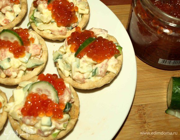 Выкладываем салат в тарталетки. Сверху на салат выкладываем красную икру и украшаем кусочком огурца или листиком петрушки. Закуска готова. 