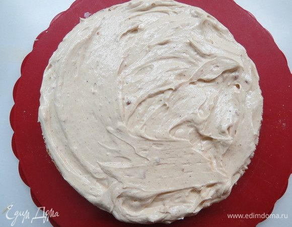 Приступаем к сборке торта. Коржи отделяем от бумаги, выкладываем первый корж и намазываем на него половину белого грильяжного крема, накрываем вторым коржом, на который намазываем оставшийся белый крем. Сверху накрываем третьим коржом. 