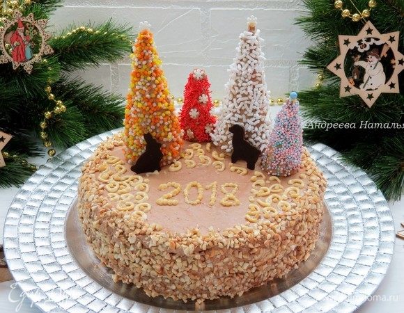 Верх и бока торта обмазываем шоколадным грильяжным кремом. Бока украшаем дроблеными орехами. Я решила украсить торт в новогоднем стиле. Для елочек обмазала вафельные рожки шоколадным кремом «Шарлотт» и обсыпала кондитерской посыпкой.  С помощью вырубок для печенья сделала шоколадные силуэты зверюшек. 