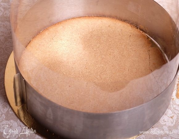 Приступить к сборке торта. Для этого стенки кольца простелить ацетатной пленкой. На дно выложить первый песочный корж. Корж может слегка раскрошиться — не переживайте, в готовом торте это будет незаметно.