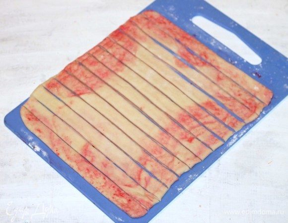 Припыляем мукой разделочную доску и раскатываем первый конвертик в пласт размером 25*30 см. Начинка немного будет вытекать, но при раскатке вся уйдет в тесто. Нарезаем полоски шириной 1,5–2,0 см. 
