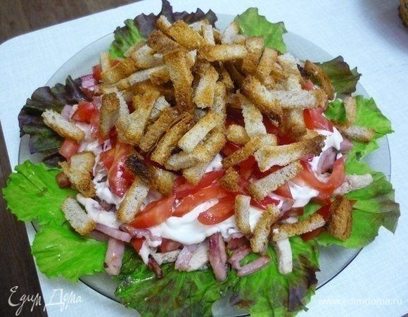 Все укладываем на плоскую тарелку слоями: обжаренное филе, половину помидоров, чтобы курица пропиталась соком, следующий слой — обжаренная ветчина, все промазываем заправкой майонез + аджика + чеснок, затем выкладываем остальную часть помидоров. Сверху перед подачей на стол выкладываем горкой гренки.
