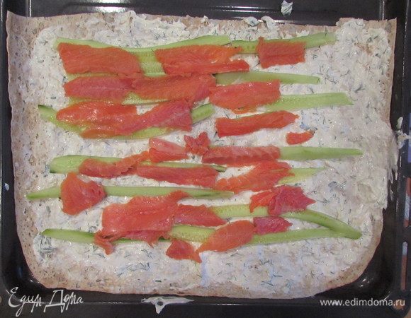 Выложить на сырную массу ломтики огурца, поверх выложить ломтики лосося.