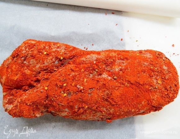 Мясо достаем из рассола, немного обсушиваем и кладем на лист пергамента. Хорошенечко со всех сторон обваливаем наше мясо в подготовленных специях. Сверху для аромата кладем пару веточек свежего розмарина.
