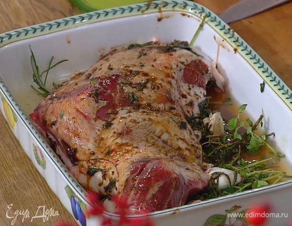 Баранину натереть со всех сторон маринадом и поместить на травы с чесноком, влить в форму куриный бульон.