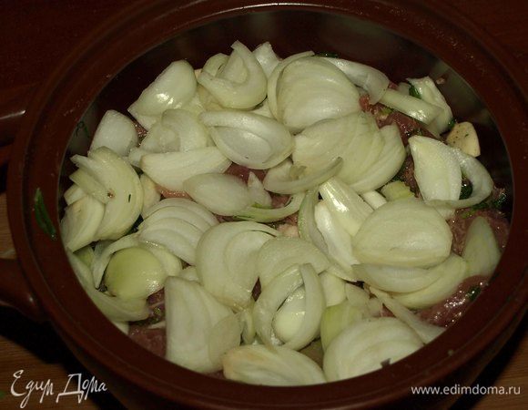 Мясо перекладываем в жаропрочную посуду. Лук очистить и крупно нарезать. Закрыть луком мясо. Закрываем крышкой. 