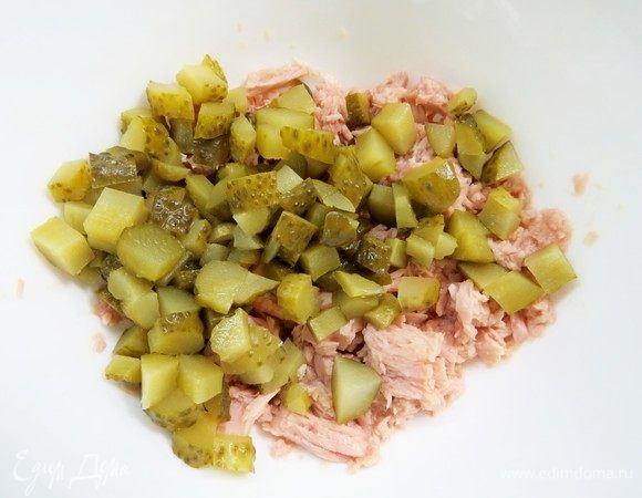 Мелко нарезать маринованные огурчики, добавить к тунцу.