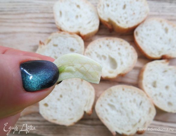 Дольки чеснока почистить, разрезать чеснок пополам и сделать ножом решеточку, чтобы чеснок дал сок. Протереть таким чесночком каждый кусочек багета с двух сторон. 