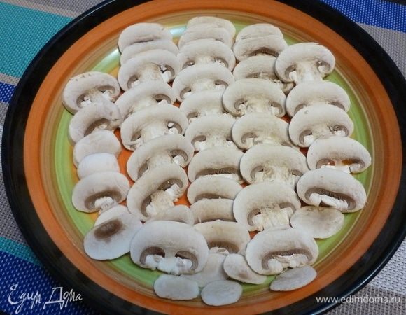 Очень свежие шампиньоны нарезать на пластинки толщиной примерно 1–1,5 мм. Выложить в один слой в тарелку.
Я снимаю верхнюю шкурку с грибов, мало ли где они лежали! Многие предпочитают протирать грибы салфеткой, но я так не делаю.