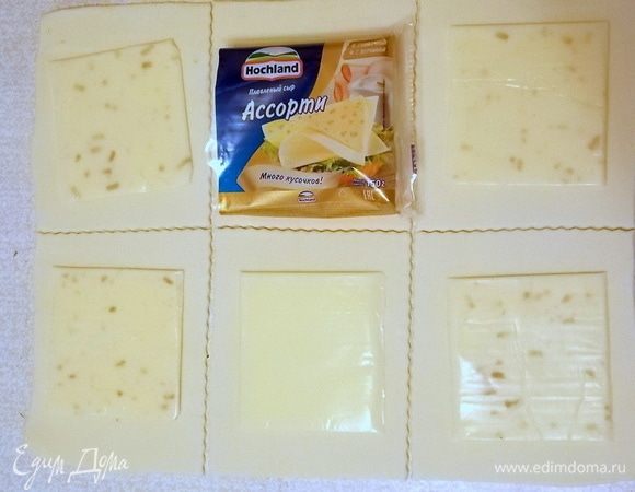 Тесто разморозить, раскатать и разрезать на 12 квадратов. На каждый положить по пластинке сыра Hochland.