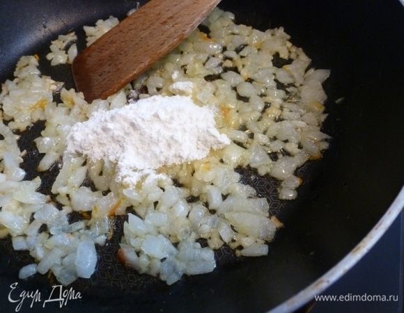 Лук и чеснок нарезать и поджарить на сковороде до мягкости и золотистости. Добавить муку, хорошо перемешать и обжарить еще минутку.