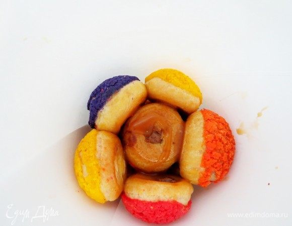 Берем самую маленькую и ровную пироженку и укладываем ее в конус кракелином вниз. Это будет верхушкой нашей елочки. Далее выкладываем три пироженки цветными сторонами к стенкам конуса. 
Пирожные можно скреплять растопленным шоколадом или карамелью. Я использовала и то, и другое. Шоколад схватывает лучше.