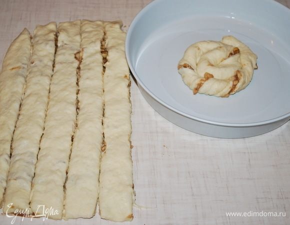 Свернуть полоски теста в жгутики и уложить в смазанную форму по кругу.