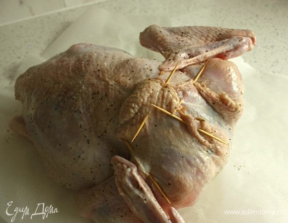 Работая на большом куске пергамента, загнуть концы крыльев индейки под тушку к спинке. Посыпать 0,5 ч. л. смеси соли и перца, внутри и снаружи. Заполнить частью начинки шейную полость, прикрыть кожным лоскутом и закрепить его зубочистками.