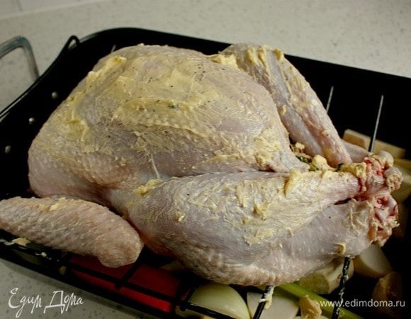 Сверху установить решетку и положить на нее индейку грудкой вверх. Посыпать оставшейся солью с перцем.