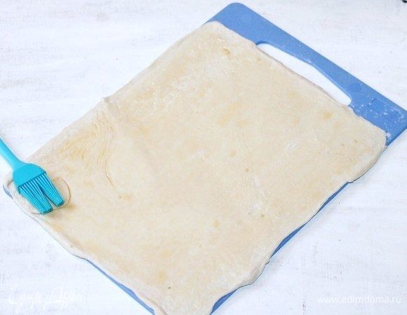 Напыляем мукой разделочную доску и раскатываем слоеное тесто до увеличения в два раза.
