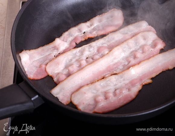 За это время разогреть сковороду и выложить в нее полоски бекона.