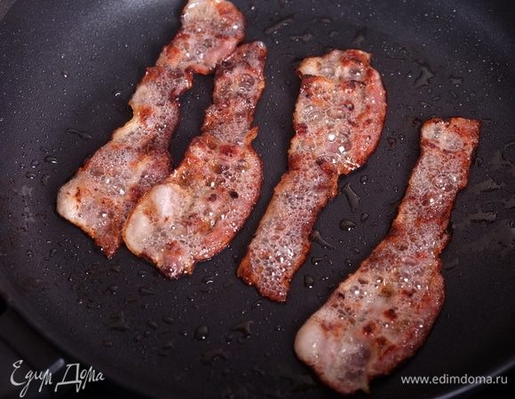 Обжарить бекон до золотистого и хрустящего состояния, выложить на бумажные полотенца, остудить, мелко порезать.