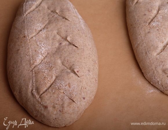 Перевернуть батоны на бумагу для выпечки, быстрыми движениями сделать надрезы и сразу же поместить батоны в печь на камень. Тут же осторожно вылить 1/2 ст. кипятка в емкость для пара (сковорода), закрыть духовку, печь с паром первые 15 минут.