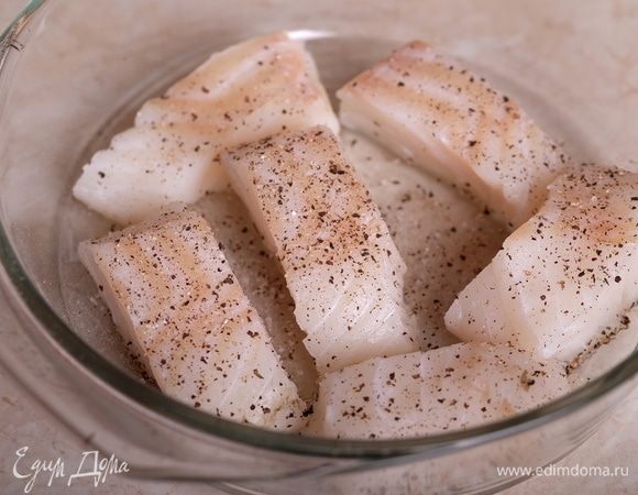 Треску промыть, порезать на порционные куски, уложить в огнеупорную форму, посолить и поперчить. Духовку разогреть до 180°С.