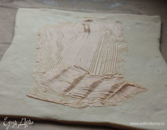 Раскатайте пласт слоеного теста. Отступите от краев примерно по 4-5 см и обильно смажьте тесто соусом с паприкой.