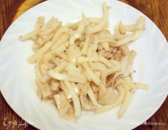 Кальмар обдать кипятком и очистить от пленки и внутренностей. Положить в соленую, кипящую воду. Довести до кипения, варить 1 минуту и слить воду. Положить в пакет, завязать и оставить до остывания. Нарезать соломкой.