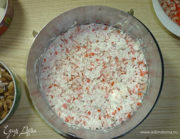 Вторым слоем укладываем крабовые палочки, нарезанные также кубиком. Промазываем майонезом. Можно оставить сетку как на первом слое.