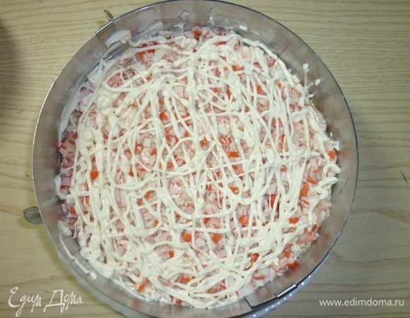 В шестом слое идут крабовые палочки и сеточка из майонеза.