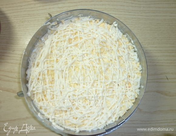 Седьмым слоем тертые на крупной терке яйца. Слегка присолить. Сверху майонезная сетка. Майонез разровнять ложкой. И следующий этап идет украшение нашего новогоднего салатика.