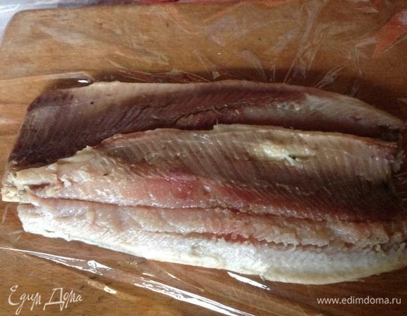Селедку разделить на 2 филе, максимально удалить косточки. Кладем 2 филе селедки валетом друг к другу и внахлест друг на друга на пленку, которая на рабочей доске.