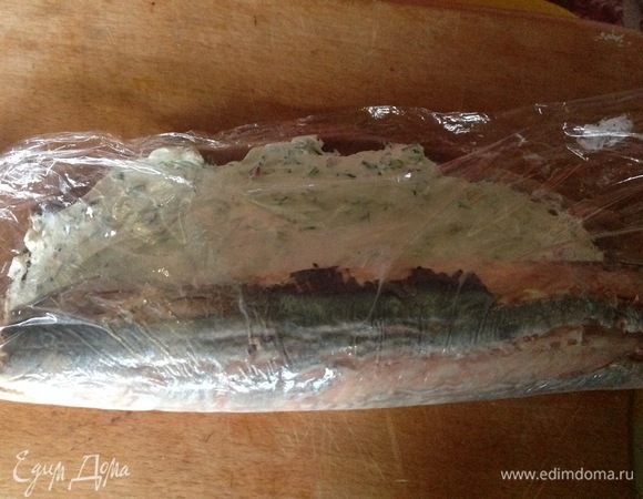 С помощью края пленки, который к нам ближе, скручиваем селедку в рулет.