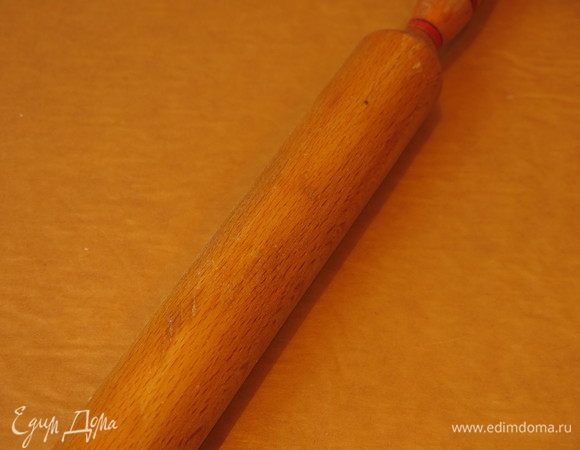 Половину теста раскатываем накрыв пергаментом. Остатки кладем в холодильник.