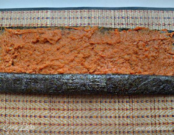 Подготовить листья нори. Мне хватило 2 листов по длине рыбы, я уложила их внахлест. Выложить листья нори на бамбуковую циновку для суши, сверху на водоросли укладываем подготовленный ярко-красный фарш. Аккуратно разровняйте фарш по поверхности и плотно скрутите в трубочку с помощью циновки, как большой ролл.