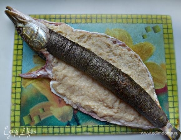 Оставшийся (без паприки) фарш равномерно распределить по коже щуки. Сверху выложить подготовленный ролл.