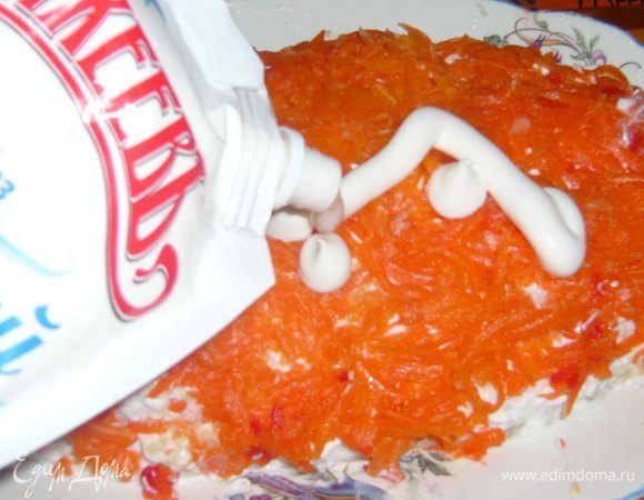 Выкладываем сверху натертую морковь и слой майонеза. Равномерно все распределяем.
