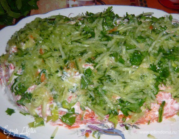 Огурец натереть на терке. Зелень мелко порубить. Слой равномерно распределяем. 