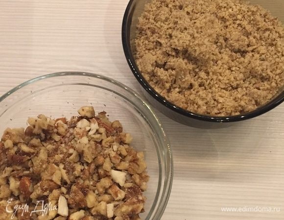 Духовку разогреть до 180°С. Измельчите 100 г орехов в мелкую крошку, почти в муку и 80 г в крупную крошку.

