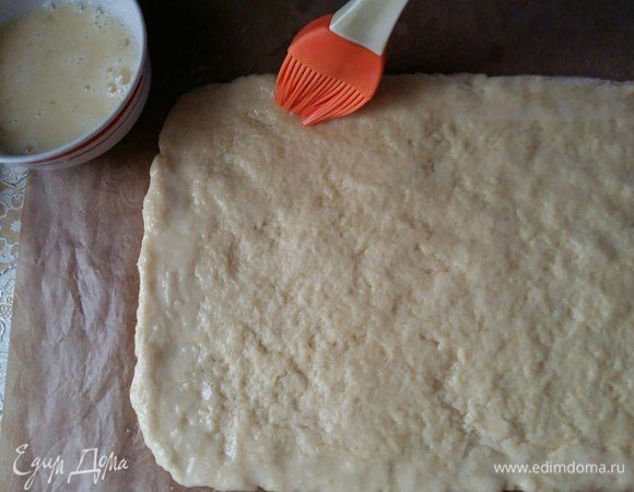 Яйцо взболтать, при помощи силиконовой кисточки смазать пласт рулета со всех сторон яйцом.