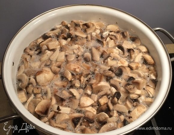 За это время приготовить начинку. Грибы вымыть, нарезать кубиком. В большой кастрюле вскипятить воду, посолить воду, добавить нарезанные грибы и отварить их около минуты. Откинуть грибы в дуршлаг, дать воде стечь.