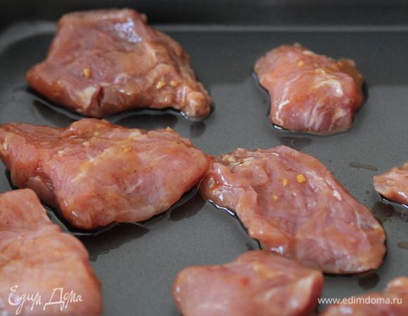 На противень вылить подсолнечное масло, выложить замаринованную свинину.