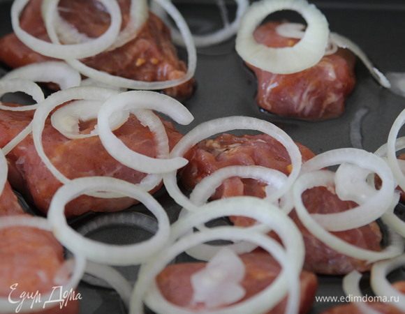 Лук нарезать кольцами и выложить на мясо.