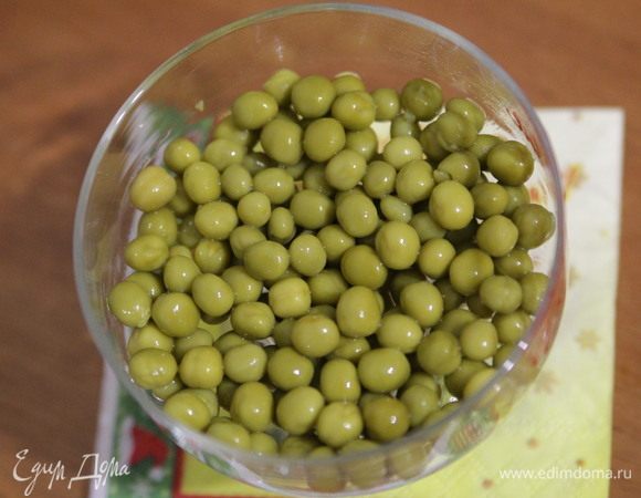 Первым слоем выложить консервированный горошек. 
