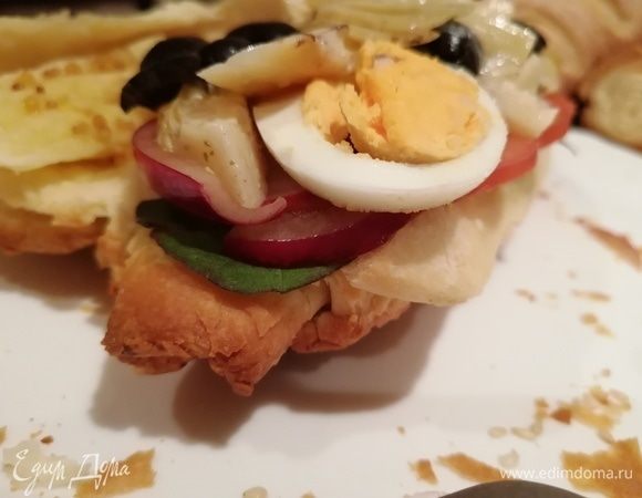 На одну половину хлеба слоями выложить салатный микс, нарезанные помидоры, редиску, лук, яйцо, артишоки и оливки.