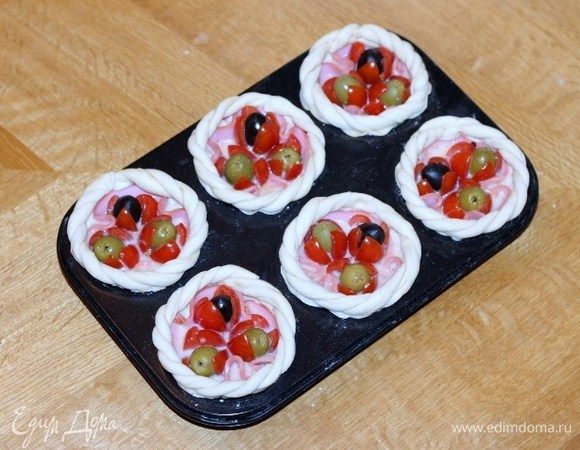 Сверху смазываем лепестки теста взбитым яйцом и украшаем жгутиками. Ставим формочки с заготовками в духовку, включаем минимальную температуру 40°С и оставляем до увеличения в 2 раза, минут 15-20.
